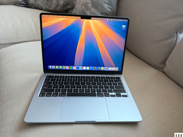 Front view of an open Apple MacBook Air 13-inch 2025  laptop sitting on a couch with the screen showing the desktop 