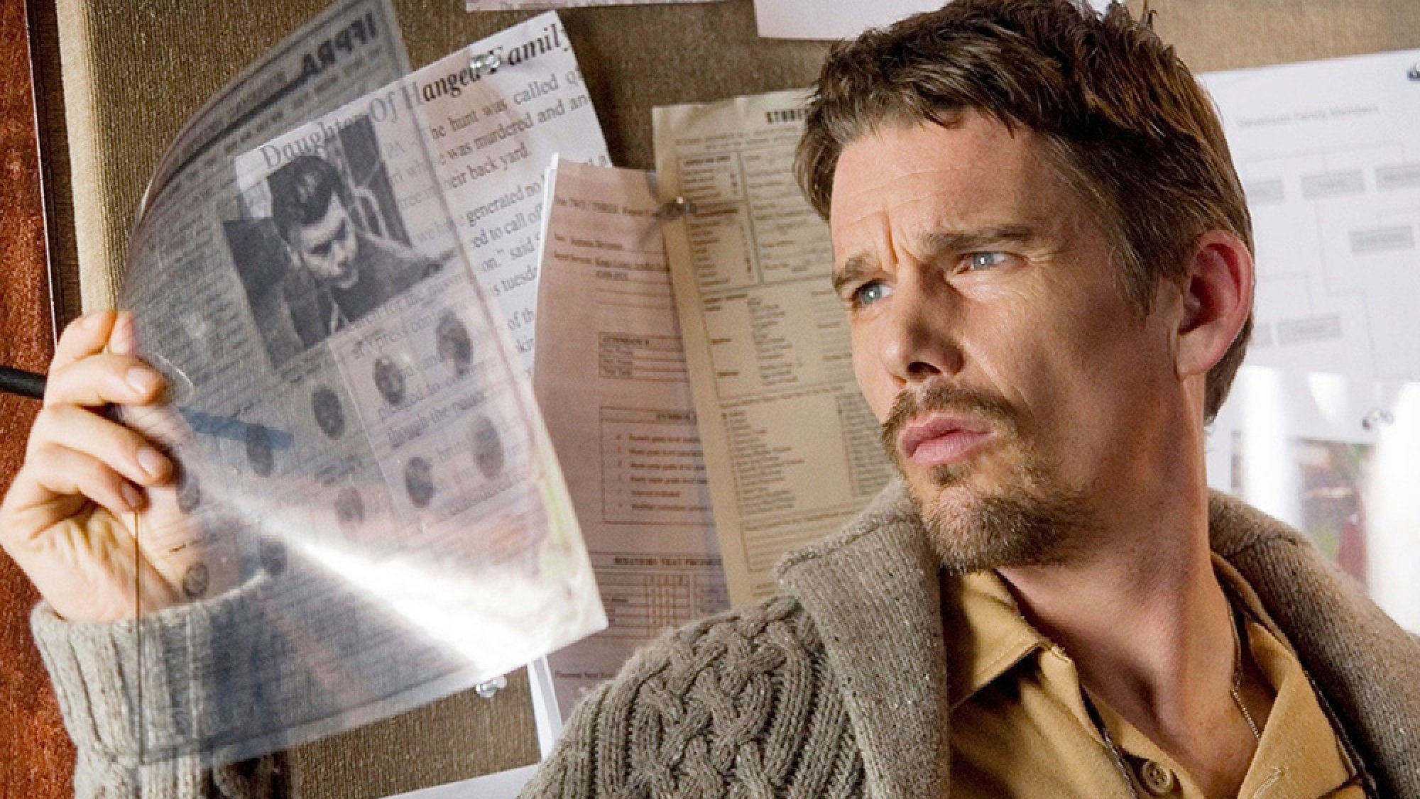 A man holds up a newspaper clipping as if investigating a story.